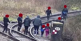 A family setting a poor example to their children while they trespass on the active railway.